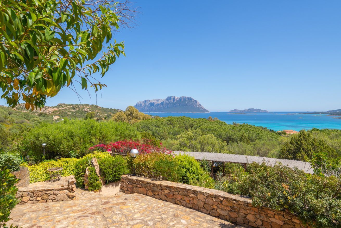 Eine Steinterrasse mit Blick auf eine gebirgige Landschaft und das Meer.