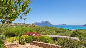 Une terrasse en pierre offrant une vue sur un paysage montagneux et la mer.