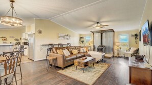A spacious living room with a brown leather sofa, wooden dining table, and a ceiling fan. - Hawkeye (Peyton)