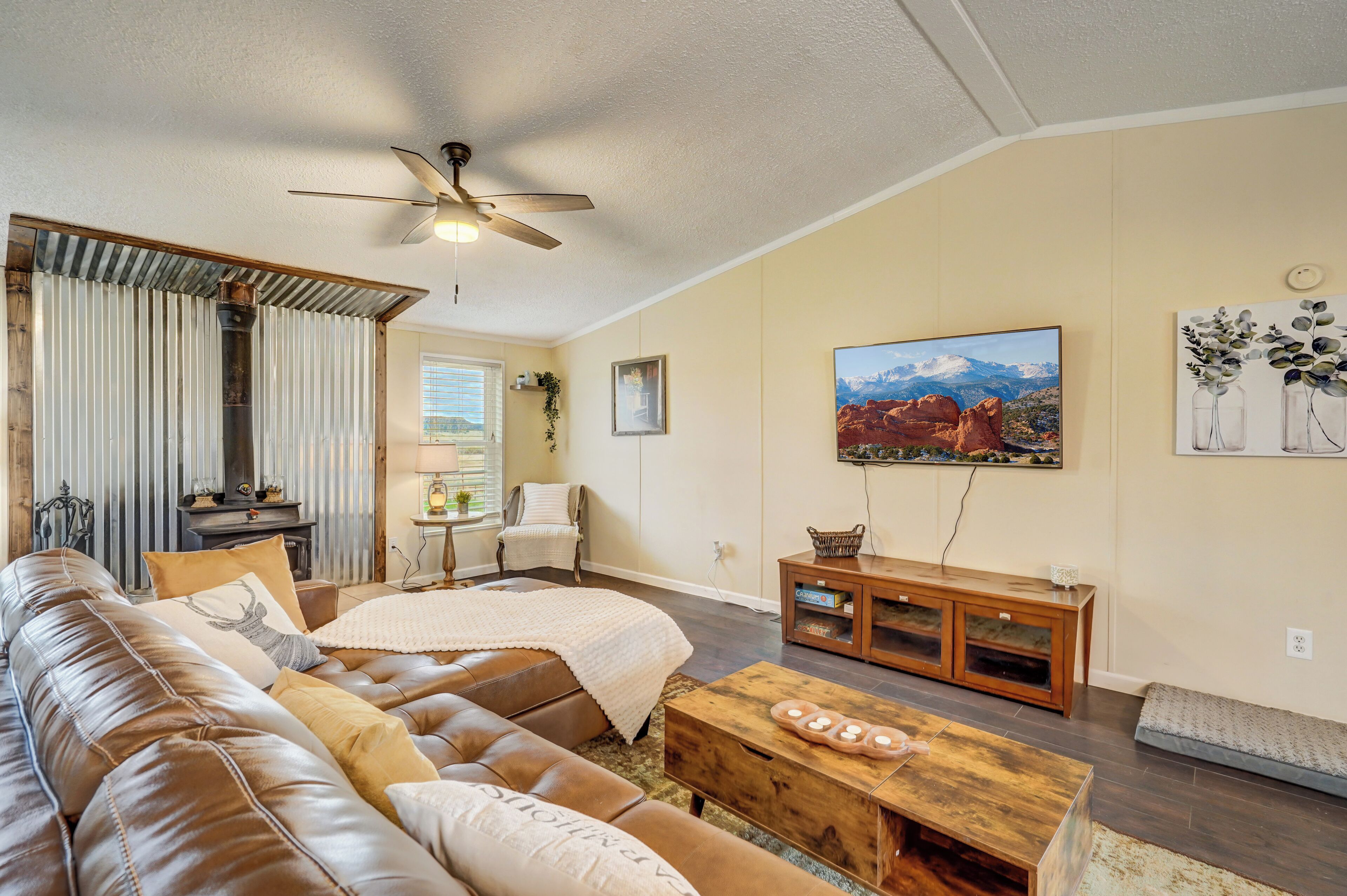 A living room with a leather couch, wooden coffee table, and a ceiling fan.