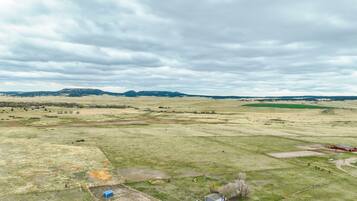 A rural landscape with a red barn, open fields, and distant hills under a cloudy sky.