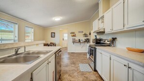 A kitchen with white cabinets, stainless steel appliances, and a beige countertop. - Hawkeye (Peyton)