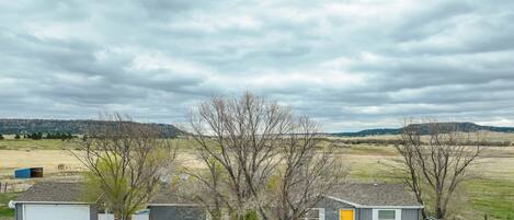 A rural property with two detached houses, one with a yellow door, surrounded by open fields and a cloudy sky.