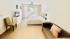 Ein Hotelzimmer mit Bett, Fernseher, Schreibtisch, Stuhl und Sofa.