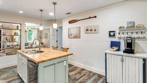 Una cocina con isla de madera, armarios blancos y una cafetera.