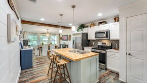 Una cocina moderna con una isla central, electrodomésticos de acero inoxidable y un suelo de madera rústica.