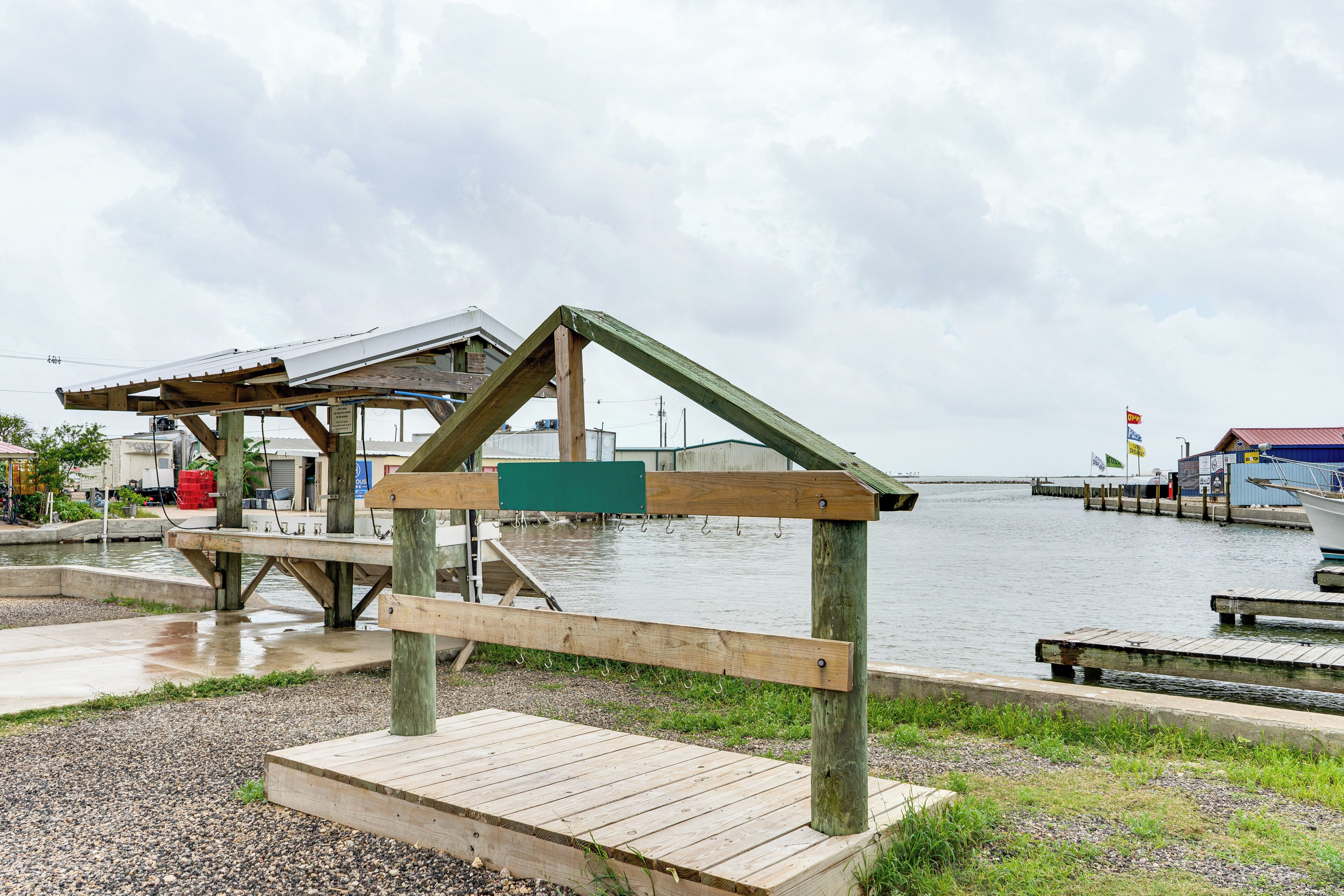A wooden pier with a bench and a covered area by a calm body of water.