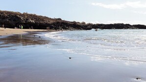 Een strand met helder water, een zandstrand en rotsachtige kliffen.