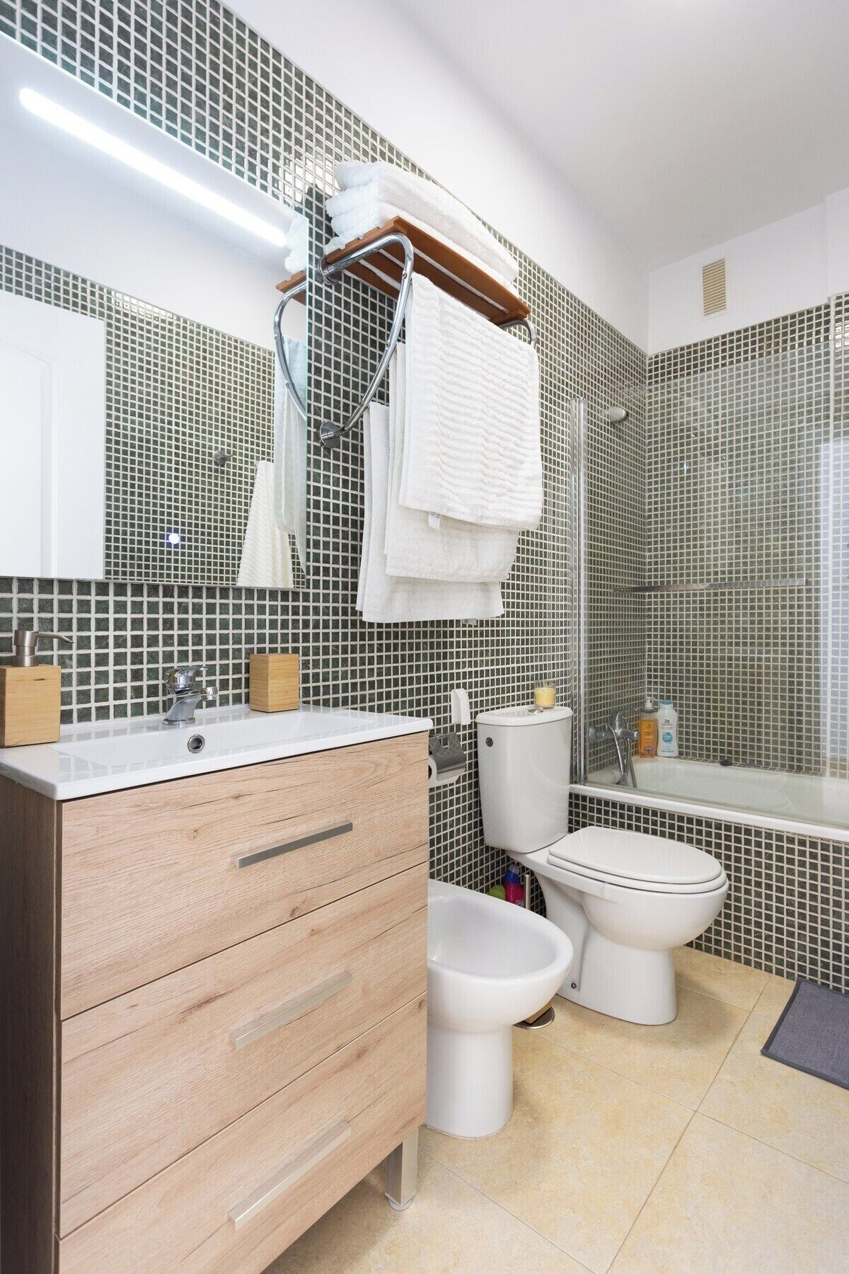 Un baño moderno con tocador de madera, inodoro, bidé y bañera.