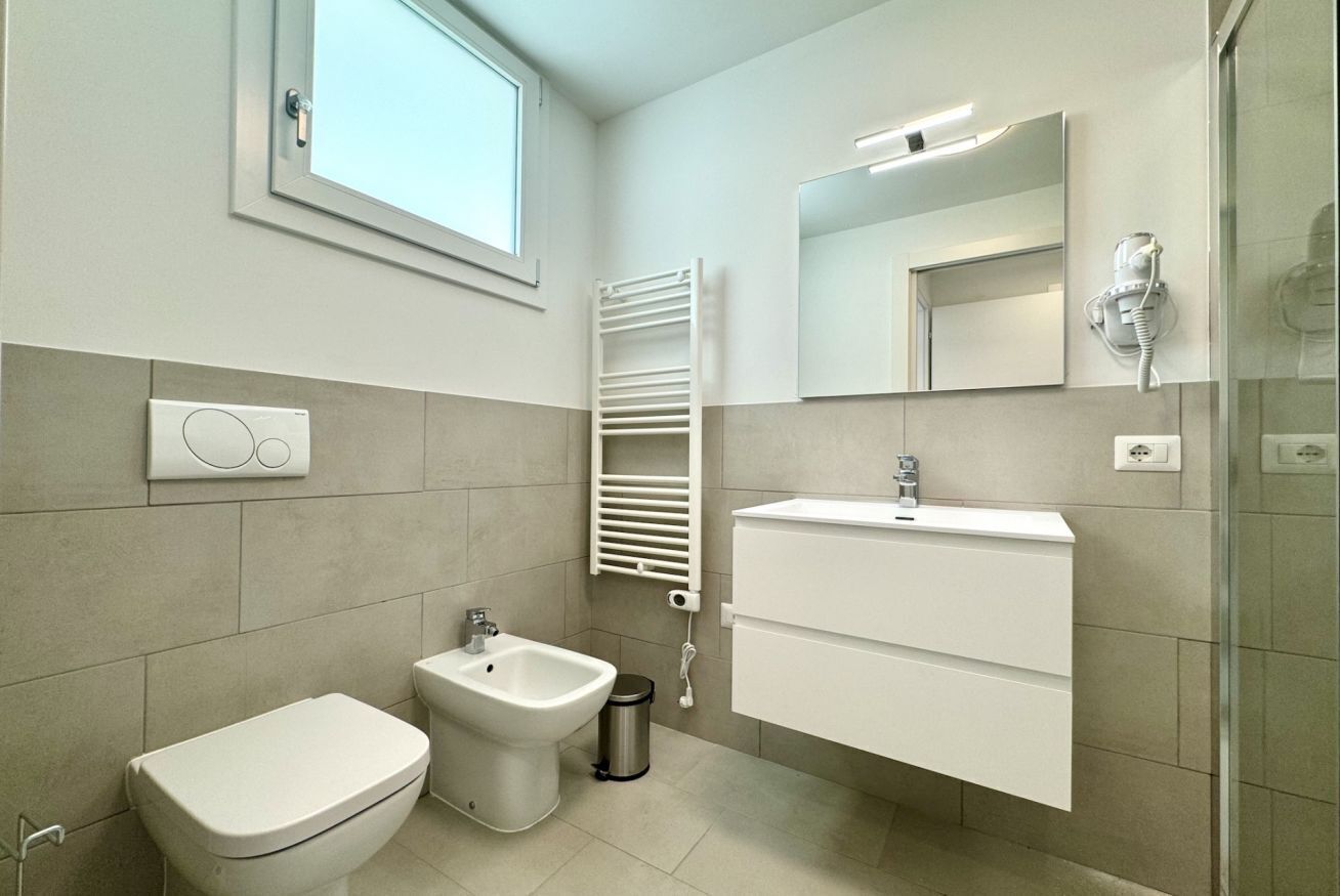 Une salle de bain moderne équipée de toilettes, d’un bidet, d’un meuble-lavabo et d’un porte-serviettes.