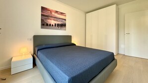 Quarto com uma cama, mesa de cabeceira, quadro na parede e guarda-roupa.