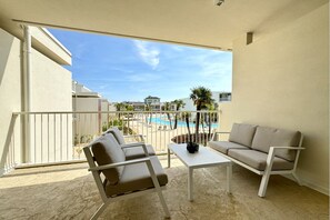 Un balcone con vista sulla piscina, due divani e un tavolino.