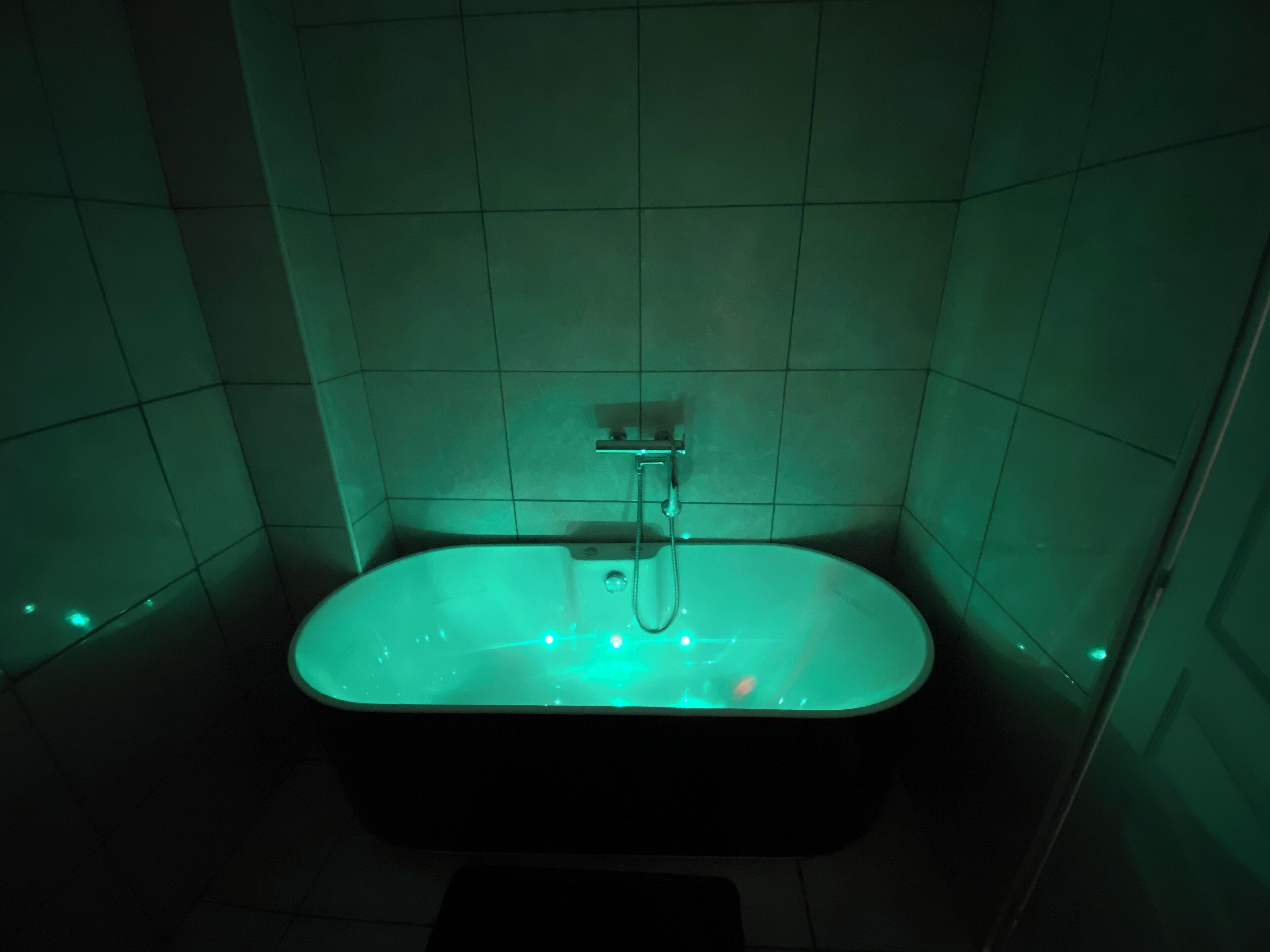 A bathtub with a showerhead in a tiled bathroom.