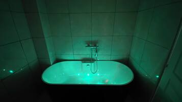 A bathtub with a showerhead in a tiled bathroom.