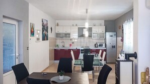 Une cuisine moderne avec des meubles blancs, un îlot central et un coin repas comprenant une table et des chaises.