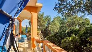 Un balcon avec des balustrades orange, un auvent bleu et une vue sur une végétation luxuriante.