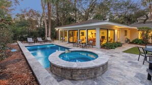 Una casa moderna con piscina, mobiliario exterior y jardín bien cuidado.