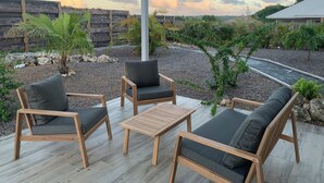 A covered patio with wooden furniture and a view of a landscaped area. - Nakolodge 2 chambres - piscine / jardin privatifs  (Sainte-Anne)