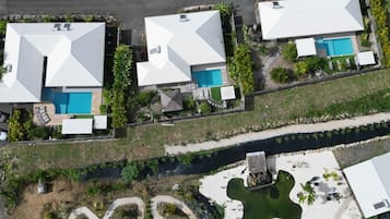 A residential area with multiple houses, each featuring a swimming pool and surrounded by greenery.