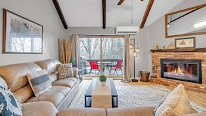 Una sala de estar acogedora con un sofá de cuero, una chimenea y un ventanal con vistas a una terraza.