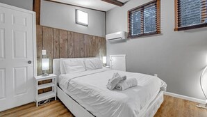 Un dormitorio con cama, mesita de noche, lámpara, armario y ventana con persianas.