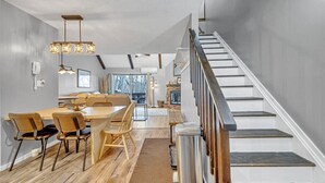 Una cocina moderna con una isla central, suelo de madera y una escalera con barandilla de madera.