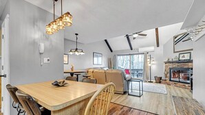 Una sala de estar moderna con chimenea, un comedor con mesa y sillas de madera, y un ventanal con vistas.