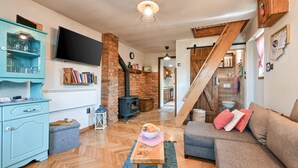 A cozy living room with a fireplace, a sofa, a television, and a staircase leading to another level.