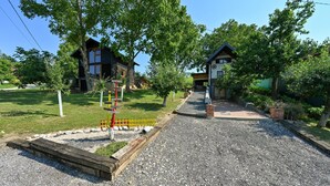 A gravel driveway leading to a wooden house with a small porch and a swing set in the background.