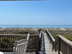 A wooden boardwalk leading to a beach with a clear view of the ocean.