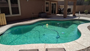 Ein Pool mit geschwungener Kante, umrahmt von einem Kiesstreifen. Im Vordergrund befinden sich zwei Liegestühle.