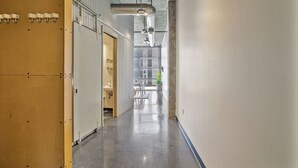 A hallway with lockers, a door leading to a bathroom, and a window with a view of the outside. - *NEW* Trendy & Central Gulch Condo! (Nashville)