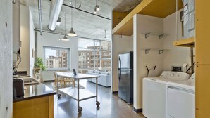 A modern kitchen with a cart, a refrigerator, and a washing machine. - Stylish 2 Bedroom in the Gulch (Nashville)