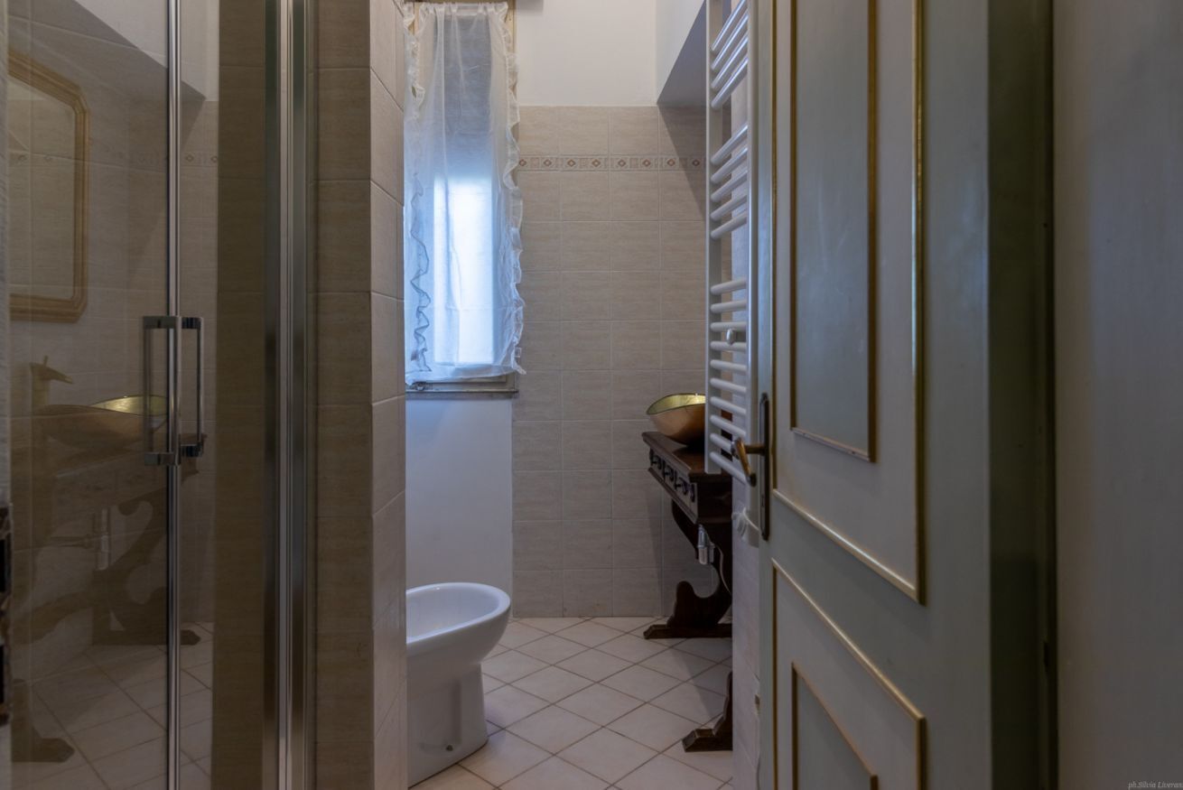 Une salle de bain dotée d’une douche à parois de verre, de toilettes et d’un lavabo avec un receveur de couleur dorée.