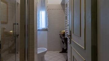 Une salle de bain dotée d’une douche à parois de verre, de toilettes et d’un lavabo avec un receveur de couleur dorée.
