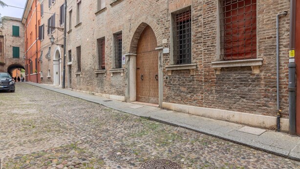 Een straat met kinderkopjes, historische gebouwen, een houten deur en een metalen poort.
