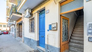 A narrow street with a blue door, a staircase, and a parked car.