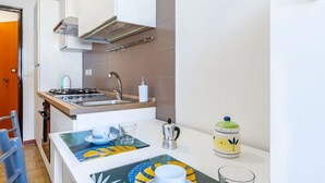A compact kitchen with a stove, sink, and a small dining area with a table and chairs.