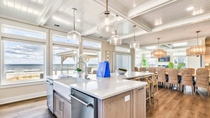 A spacious kitchen with a large island, modern appliances, and a view of the ocean. - Pura Vida | Oceanfront | Private Pool, Hot Tub, and Dog Friendly (Virginia Beach)
