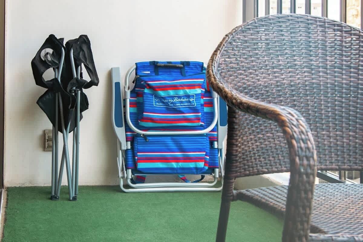 A room with a wicker chair, a blue and red striped bag, and crutches against the wall.