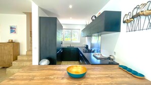 Una cucina moderna con un tavolo da pranzo in legno, una ciotola blu e una finestra che si affaccia sul verde.