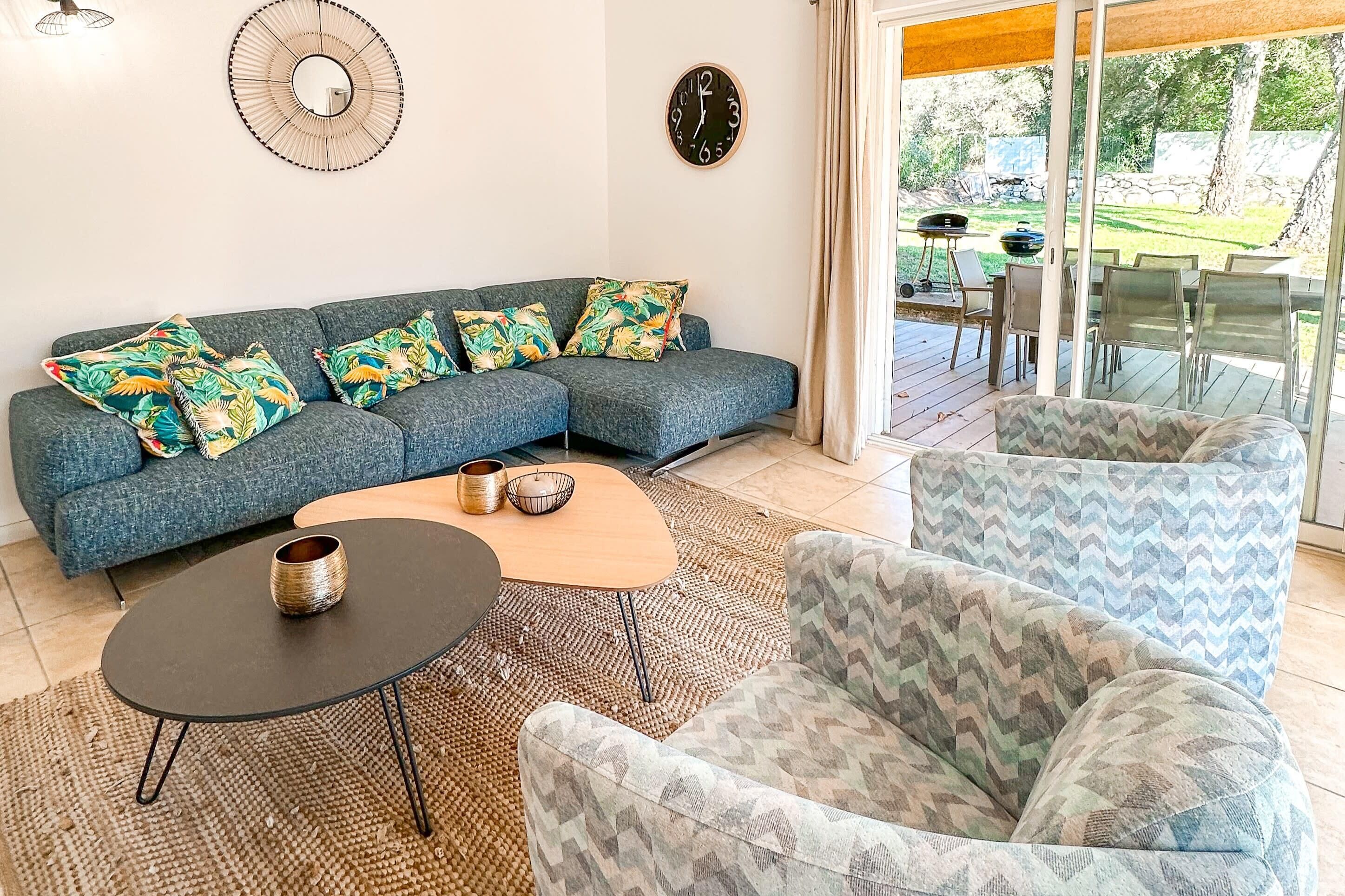 Een moderne woonkamer met een modulaire bank, decoratieve kussens, een salontafel en een gestreept fauteuil.