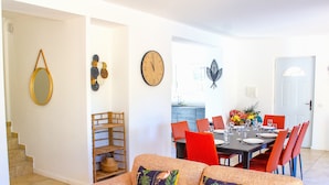 A living room with a sofa, a dining table set for four, and a kitchen in the background.