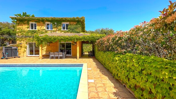 A two-story house with a swimming pool, outdoor seating, and a covered patio area.