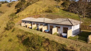 A two-story house with a tiled roof, a fenced yard, and a small garden area. - EMBAHÚ SUÍTES  (Santo Antonio do Pinhal)