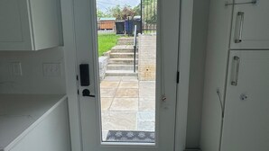 A narrow hallway leading to a door with a view of a backyard.