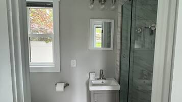 A modern bathroom with a toilet, sink, and glass-enclosed shower.