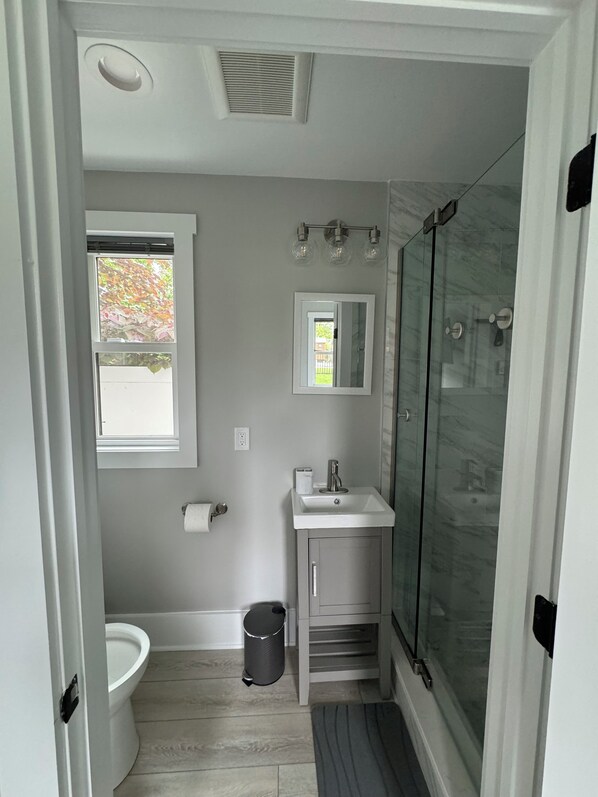 A modern bathroom with a toilet, sink, and glass-enclosed shower.
