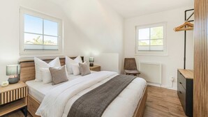 A bedroom with a bed, bedside tables, a chair, a radiator, and a wardrobe.