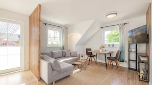 A modern living room with a sofa, dining table, chairs, and a TV.